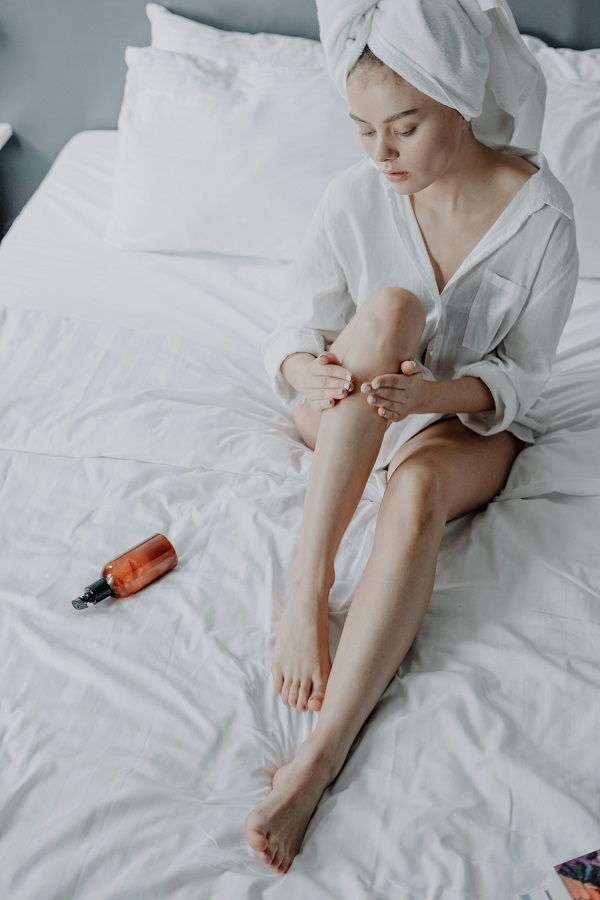 femeie aplica crema pe picioare
