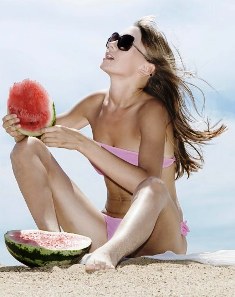 Poza femeie pe plaja savureaza pepene rosu