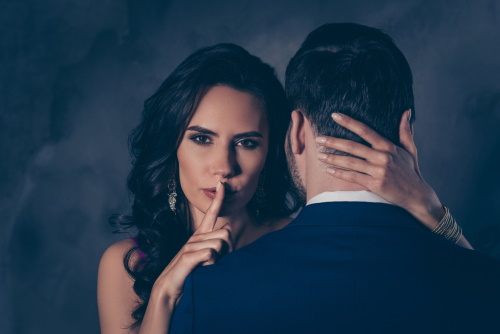 femeie care face semnul "taci" in spatele unui barbat